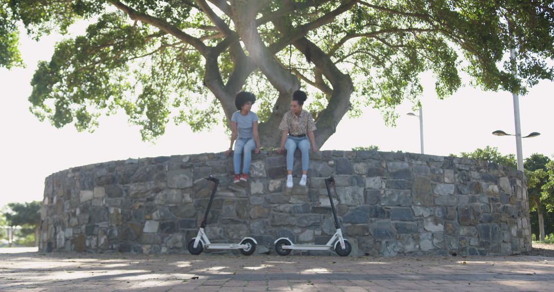 Young Friends Sitting on Wall with Electric Scooters - Free Images, Stock Photos and Pictures on Pikwizard.com