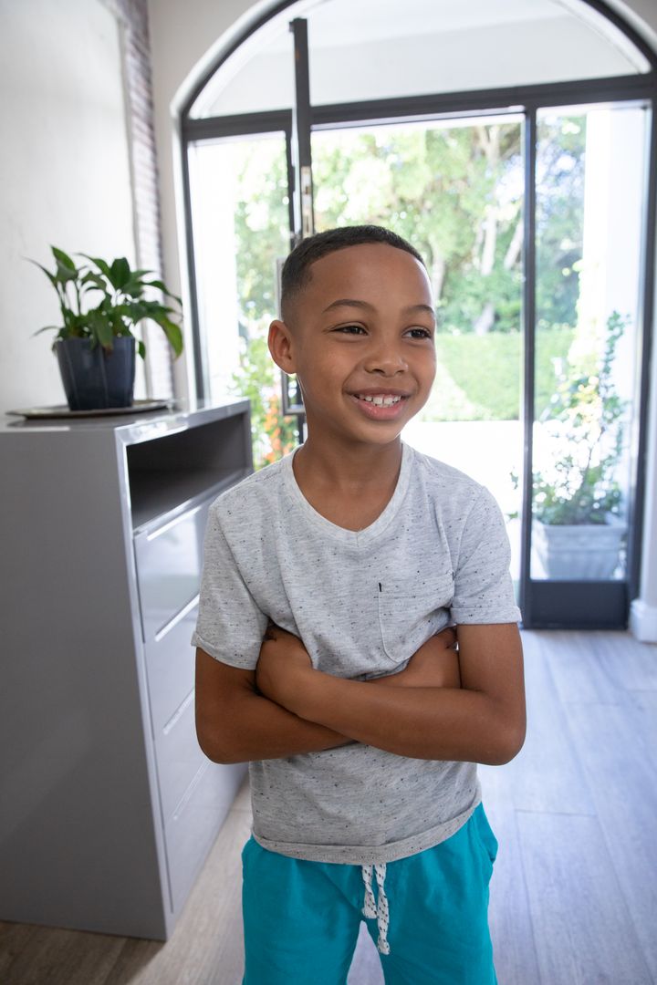 Smiling Boy in Bright Entryway Hugging Himself