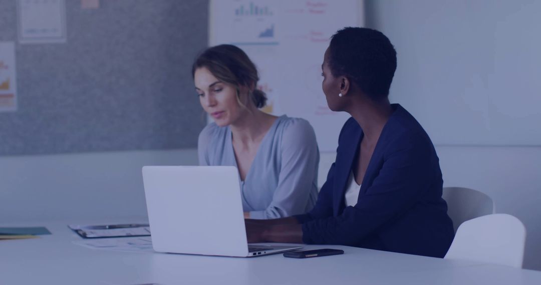 Two Businesswomen Collaborating on Project at Meeting Table