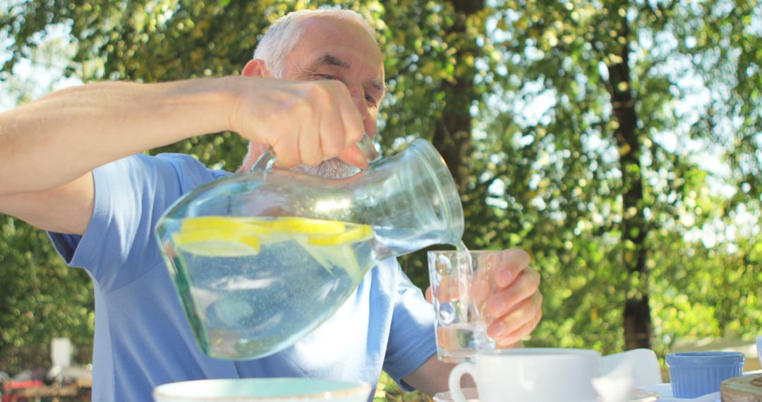 Senior Man Pouring Lemon Water Outdoors on a Sunny Day - Free Images, Stock Photos and Pictures on Pikwizard.com