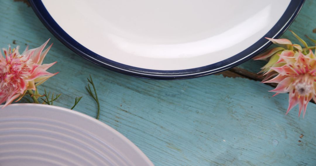 White and Blue Plates on Rustic Wooden Surface with Pink Flowers - Free Images, Stock Photos and Pictures on Pikwizard.com