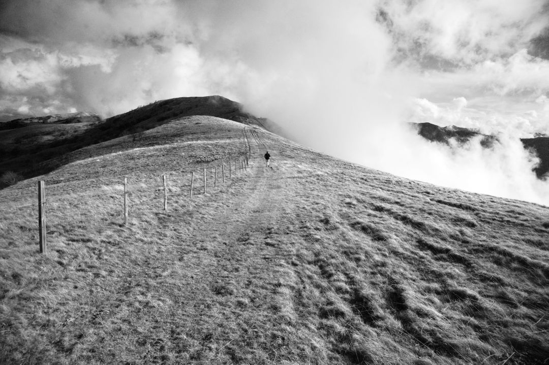 Solitary Hiker Walking on Grass Covered Hill in Remote Mountainous Landscape - Free Images, Stock Photos and Pictures on Pikwizard.com