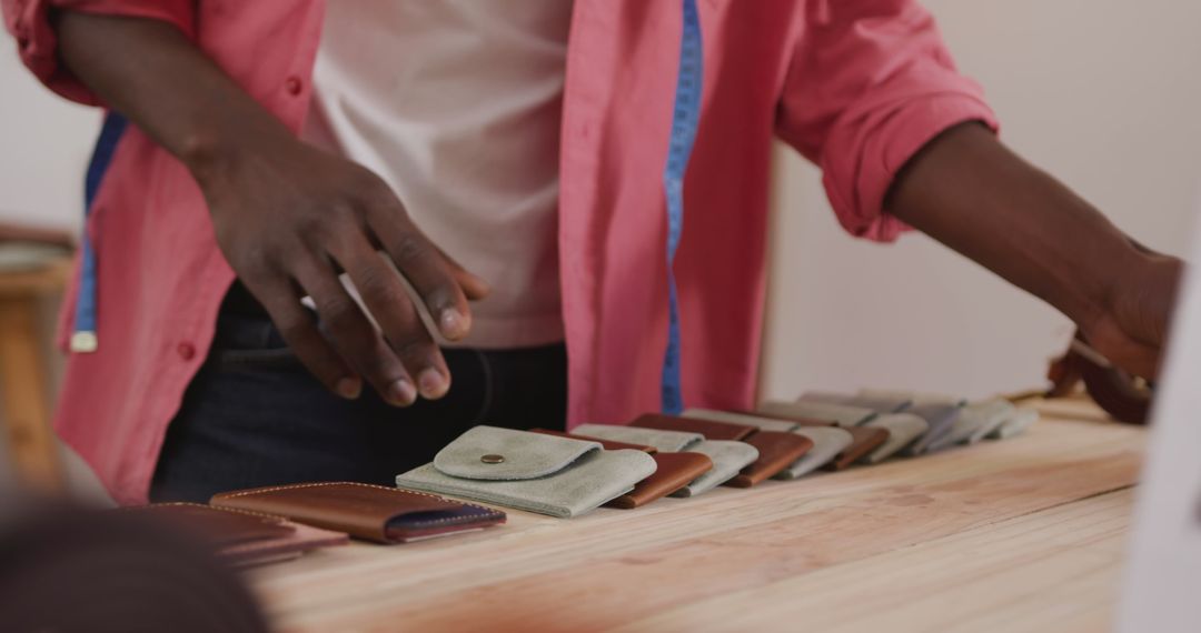 Craftsman Organizing Leather Wallets on Wooden Desk in Workshop