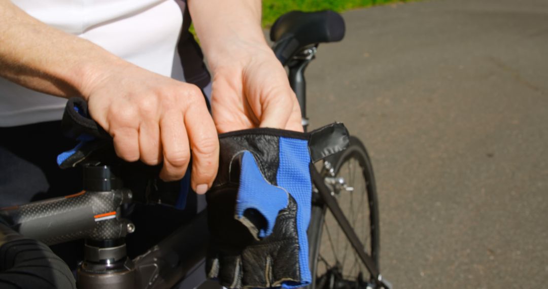 Cyclist Preparing Bicycle with Gloves on Sunny Day - Free Images, Stock Photos and Pictures on Pikwizard.com