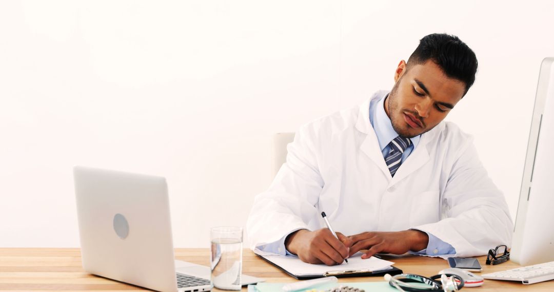 Focused Doctor Writing Medical Notes at Desk - Free Images, Stock Photos and Pictures on Pikwizard.com