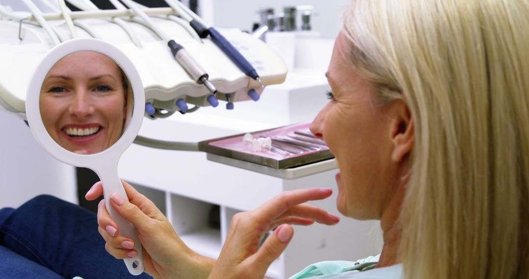 Woman at Dental Office Examining Teeth in Hand Mirror - Free Images, Stock Photos and Pictures on Pikwizard.com