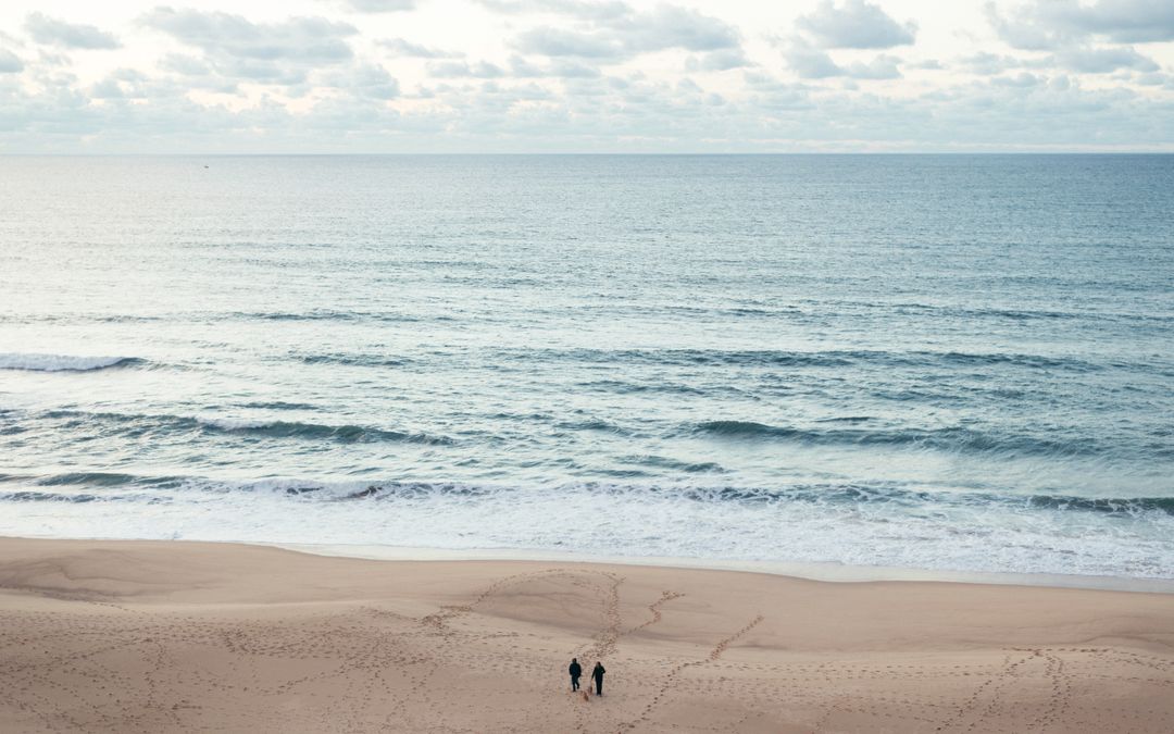 Two people walking on peaceful beach with vast ocean view - Free Images, Stock Photos and Pictures on Pikwizard.com