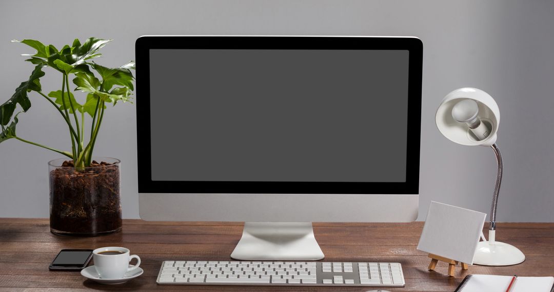 Desktop Setup with Monitor, Coffee and Plant in Modern Office