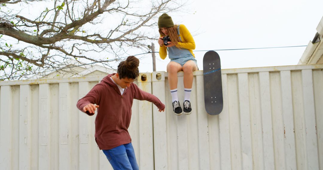 Teen girl photographing boy doing skateboard trick - Free Images, Stock Photos and Pictures on Pikwizard.com