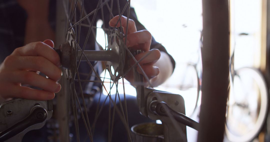 Person repairing bicycle wheel with focused attention in workshop setting - Free Images, Stock Photos and Pictures on Pikwizard.com