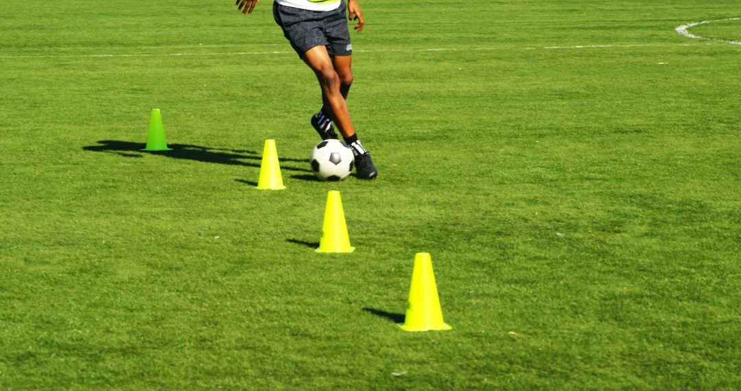 Football Player Dribbling Ball Through Training Cones On Green Field - Free Images, Stock Photos and Pictures on Pikwizard.com