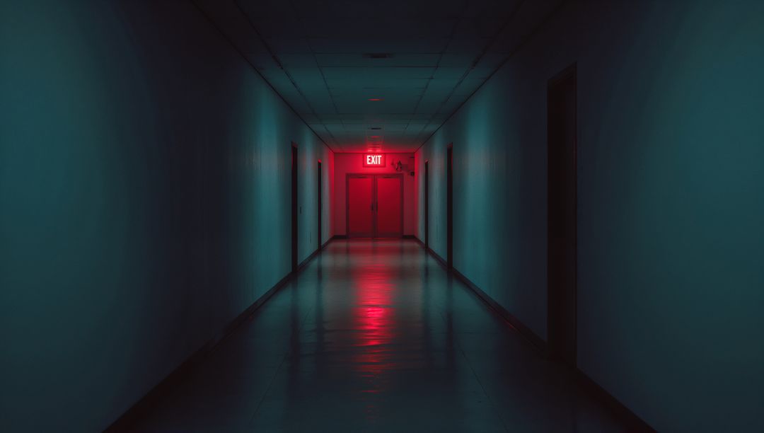 Mysterious Dimly Lit Hallway Ending with Red Exit Sign