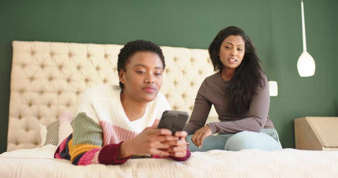 Diverse Friends Relaxing with Smartphone on Tufted Bed