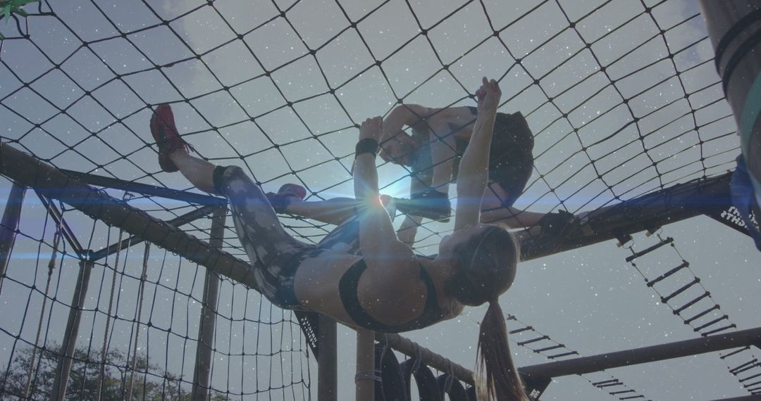 Duo Climbing on Obstacle Course Net Demonstrating Teamwork and Strength