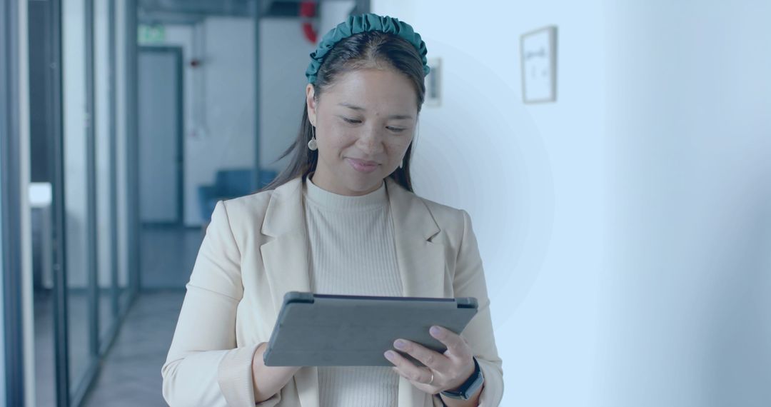 Professional Asian Woman Using Tablet in Modern Office Corridor