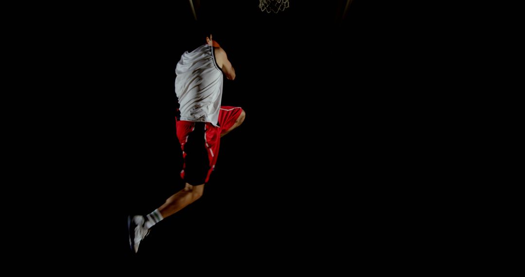 Basketball Player Jumping to Dunk in Black Background - Free Images, Stock Photos and Pictures on Pikwizard.com