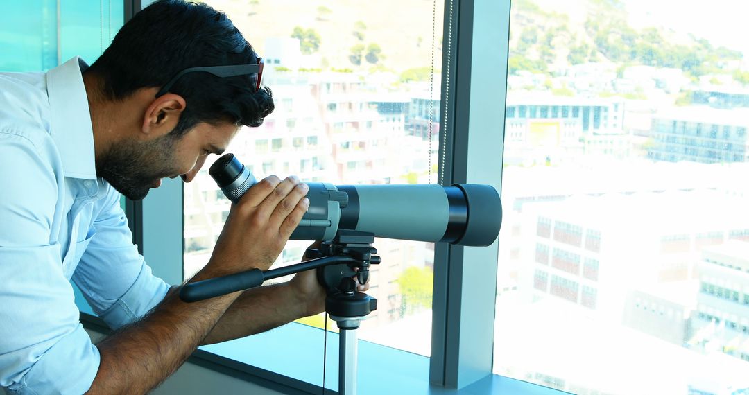 Man Using Telescope By Office Window - Free Images, Stock Photos and Pictures on Pikwizard.com