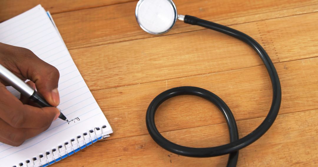 Stethoscope and Hand Writing in Notebook on Wooden Table - Free Images, Stock Photos and Pictures on Pikwizard.com