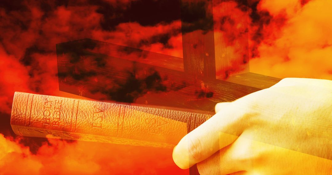 Silhouette of Cross with Hand Holding Bible Against Fiery Sky