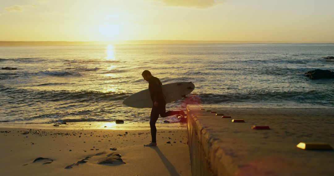 Surfer Walking Along Beach at Sunset with Surfboard - Free Images, Stock Photos and Pictures on Pikwizard.com