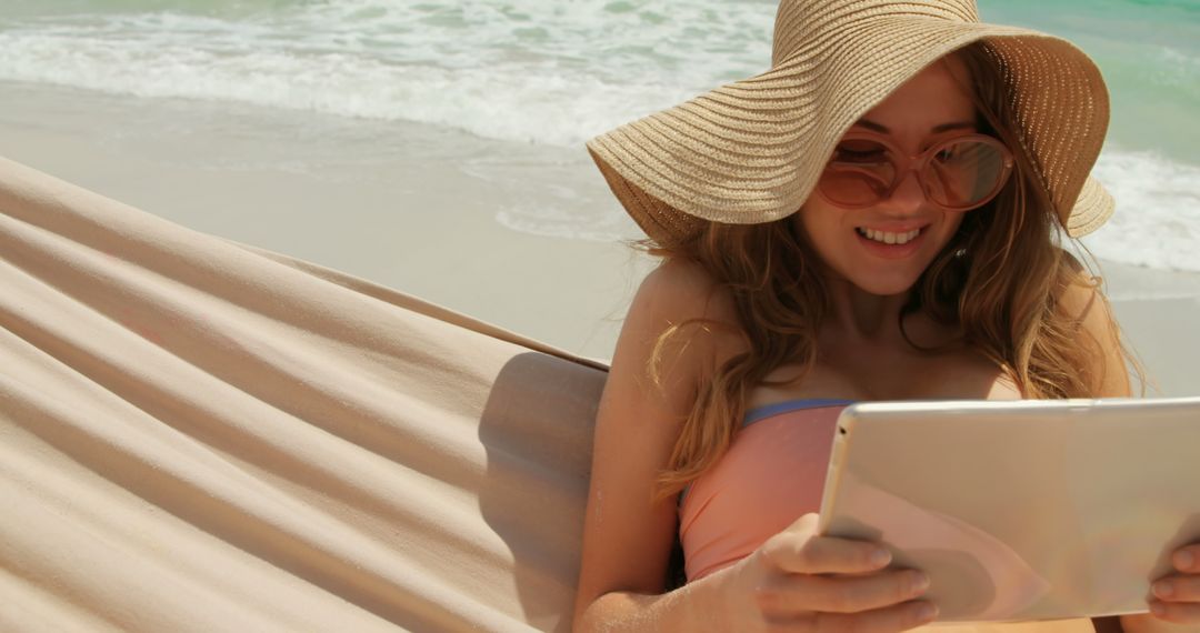 Smiling Woman Relaxing with Tablet in Hammock by Beach