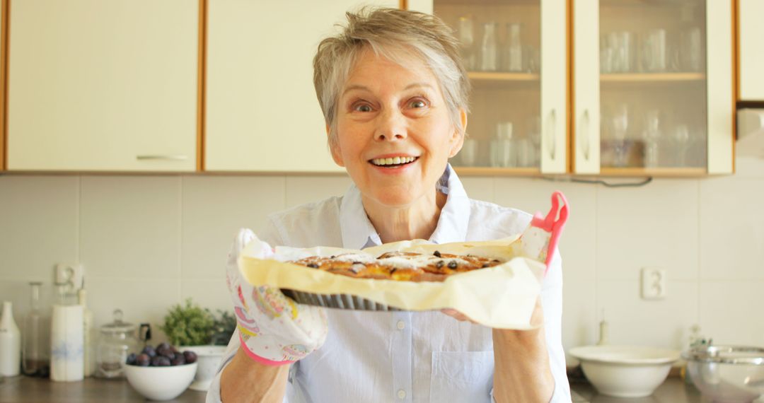 Happy Senior Woman Holding Freshly Baked Pie in Kitchen - Free Images, Stock Photos and Pictures on Pikwizard.com