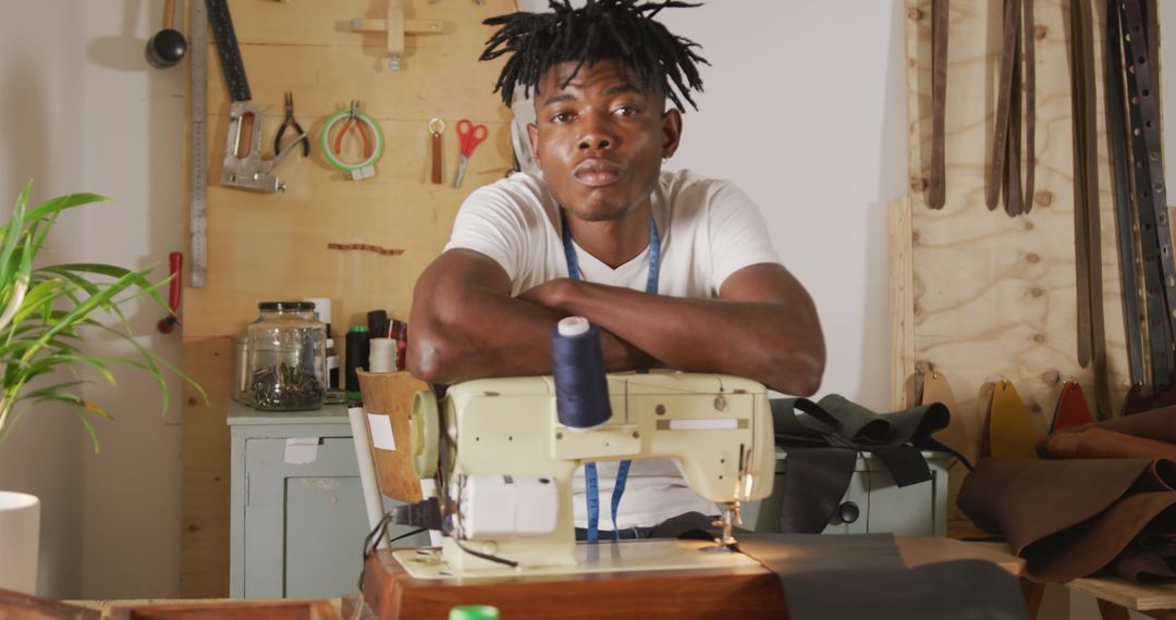 African American Craftsman with Dreadlocks Resting on Sewing Machine in Workshop