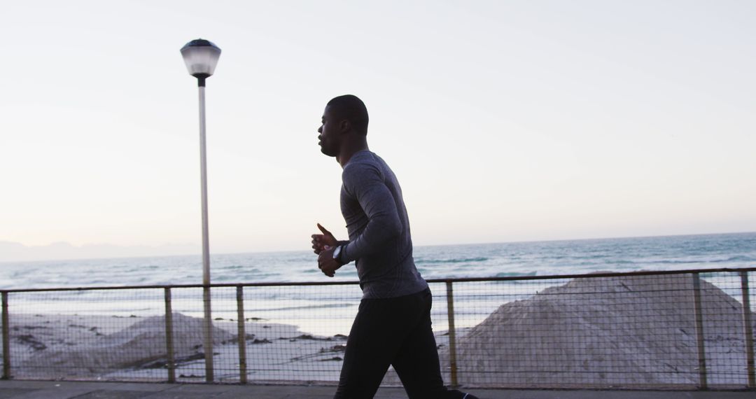 African American man jogging by ocean at sunrise - Free Images, Stock Photos and Pictures on Pikwizard.com