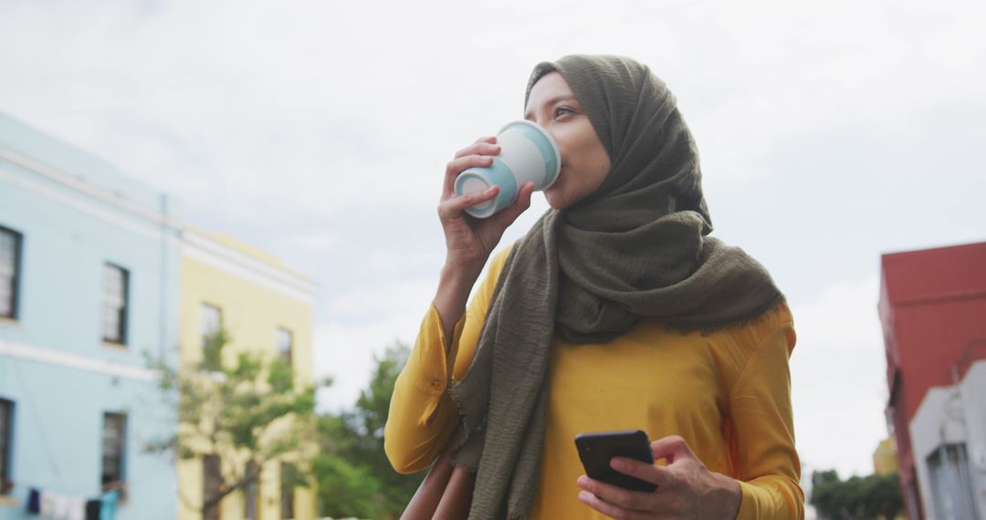 Woman Wearing Hijab Drinking Coffee Outdoors, Holding Smartphone - Free Images, Stock Photos and Pictures on Pikwizard.com