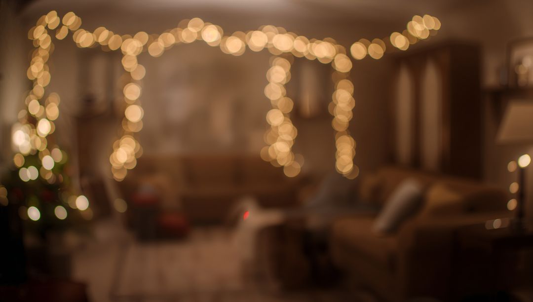 Warm string lights creating golden bokeh over cozy living room with holiday tree