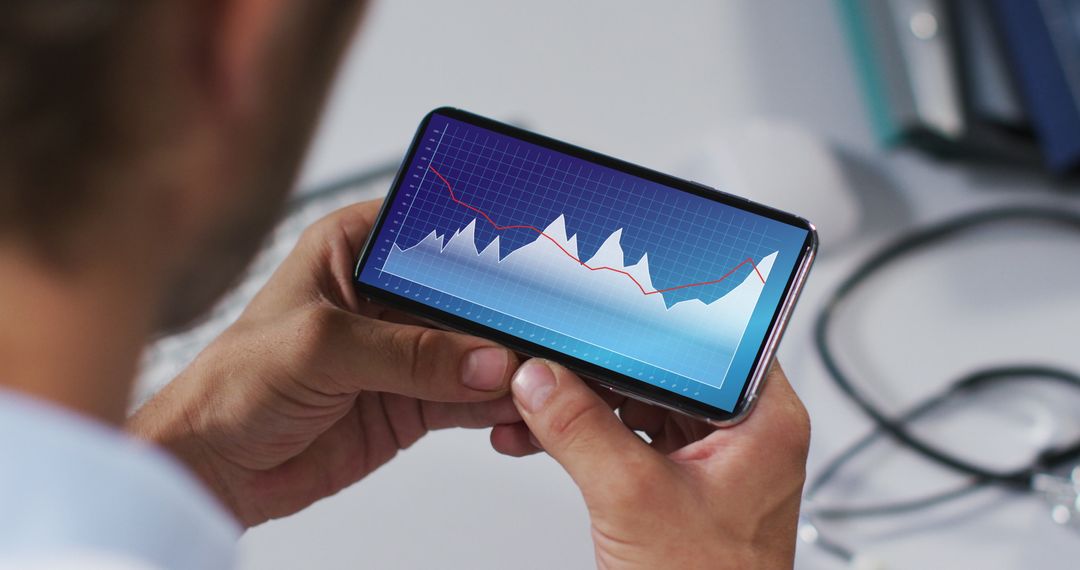 Hands Holding Smartphone Displaying Financial Graph