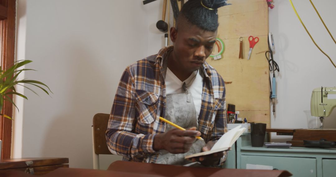 Craftsman Writing Notes in Leather Workshop