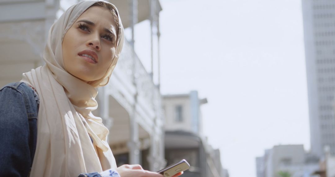 Muslim Woman in Hijab Exploring Urban Cityscape with Smartphone