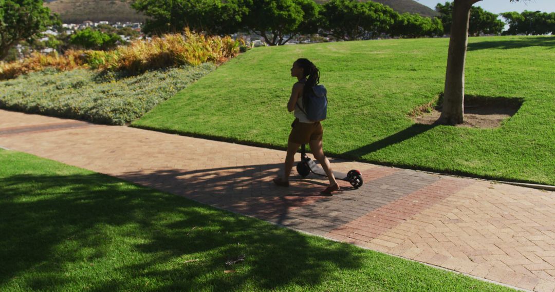 Person Walking in Park with Electric Scooter on Sunny Day - Free Images, Stock Photos and Pictures on Pikwizard.com