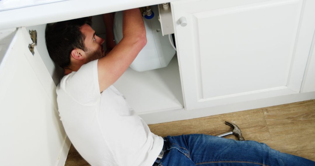 Man Fixing Sink Pipes Under Kitchen Cabinet - Free Images, Stock Photos and Pictures on Pikwizard.com