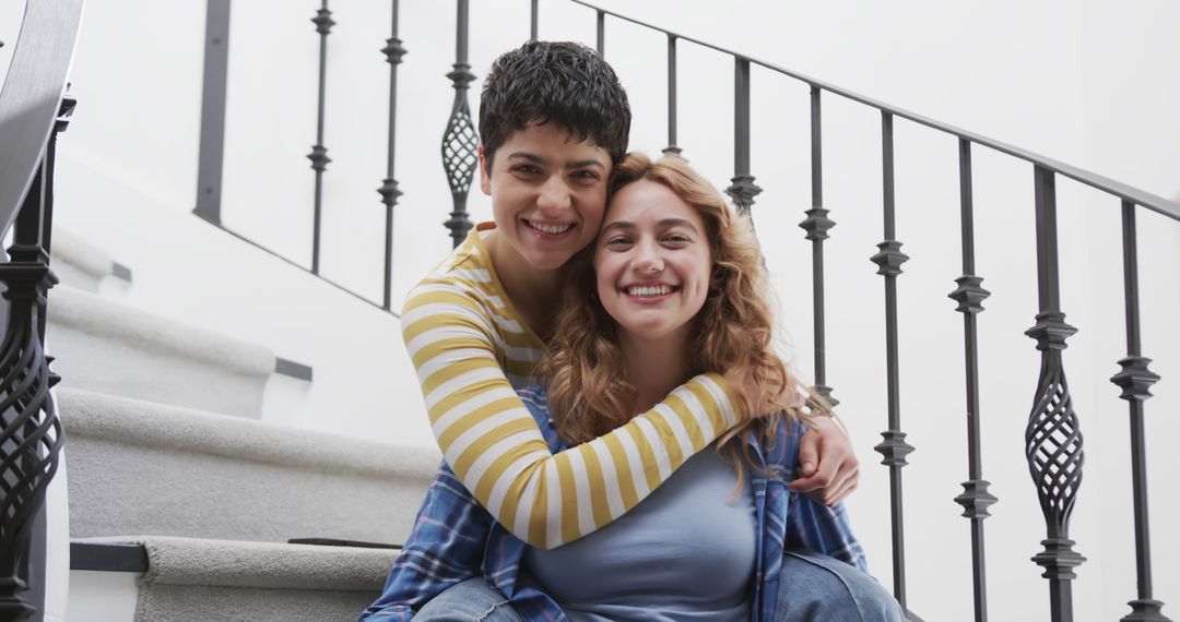 Two Women Smiling and Embracing on Staircase - Free Images, Stock Photos and Pictures on Pikwizard.com