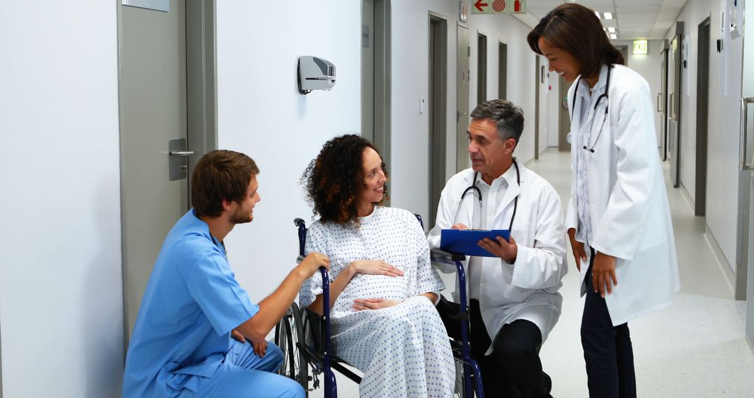 Medical Team Discussing With Pregnant Woman in Hospital Corridor - Free Images, Stock Photos and Pictures on Pikwizard.com