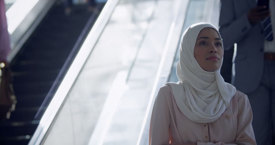 Confident Hijabi Woman Standing by Escalator in Modern Building - Free Images, Stock Photos and Pictures on Pikwizard.com