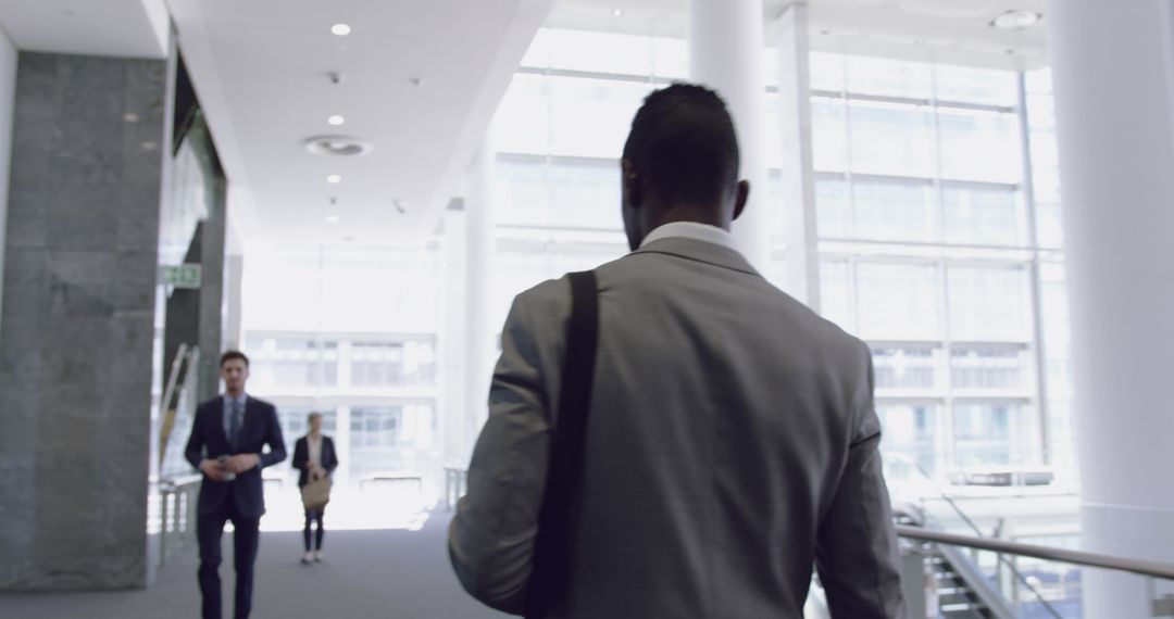 Businessman Walking Through Corporate Lobby in Office - Free Images, Stock Photos and Pictures on Pikwizard.com