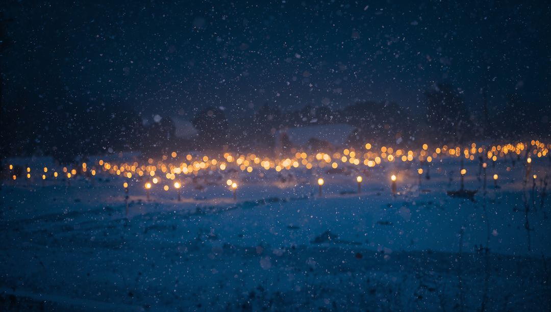 Glowing Lanterns Lighting Snowy Field at Night with Falling Snow and Warm Bokeh