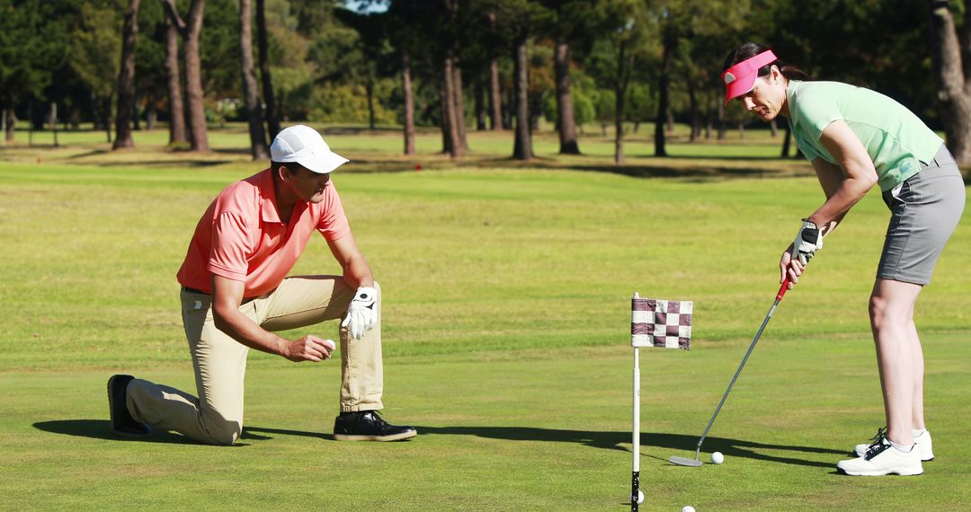 Golf Instructor Training Female Player on Putting Green During Sunny Day - Free Images, Stock Photos and Pictures on Pikwizard.com