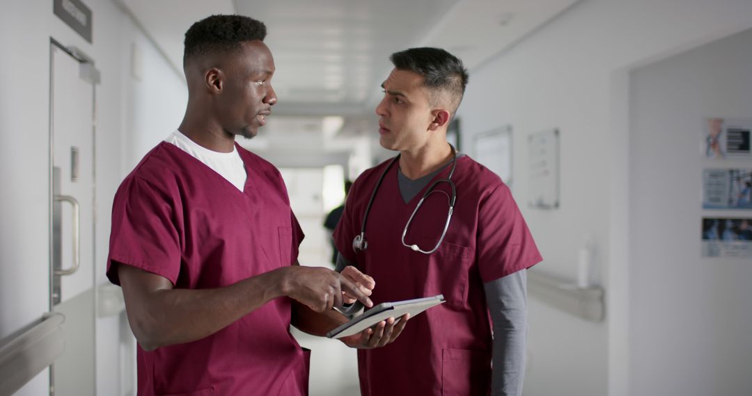 African American and Hispanic Nurses Discussing Patient Data in Hospital Hallway - Free Images, Stock Photos and Pictures on Pikwizard.com