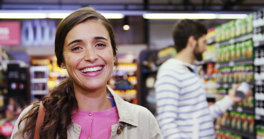 Smiling woman in grocery store aisle with male shopper in background - Free Images, Stock Photos and Pictures on Pikwizard.com