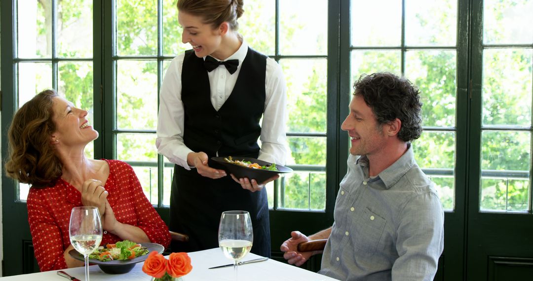 Couple Enjoying Lunch with Smiling Waitress in Bright Restaurant