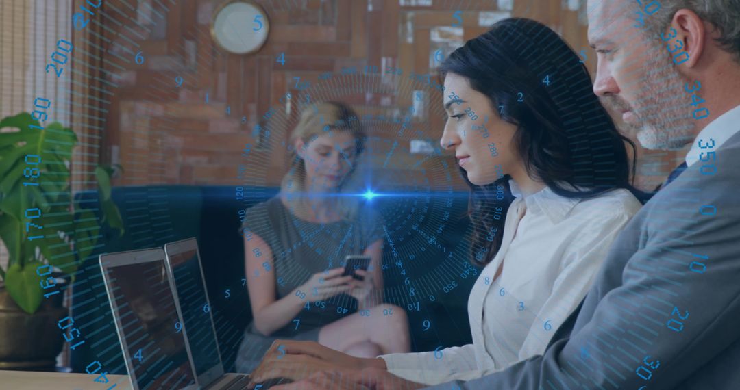 Collaborating professionals typing on laptop with futuristic HUD data overlay in coworking