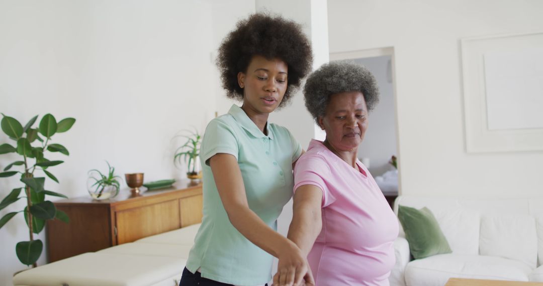 Young Caregiver Assisting Senior Woman with Arm Exercise at Home - Free Images, Stock Photos and Pictures on Pikwizard.com