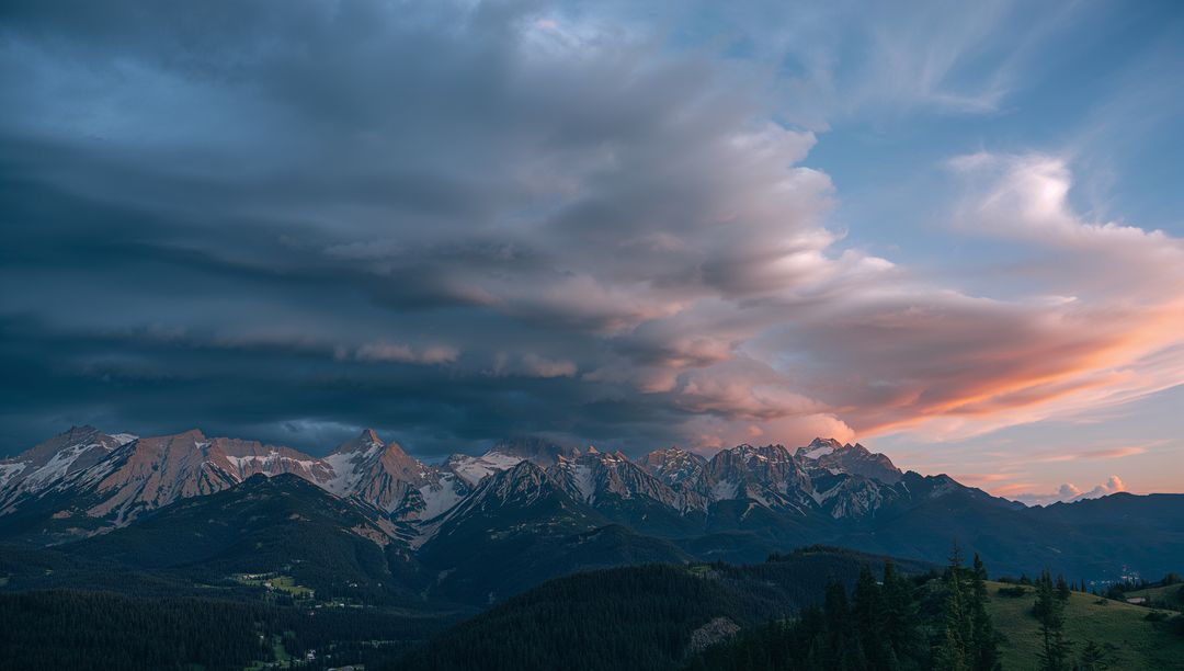 Snow-Capped Mountain Range Under Dramatic Dusk Sky
