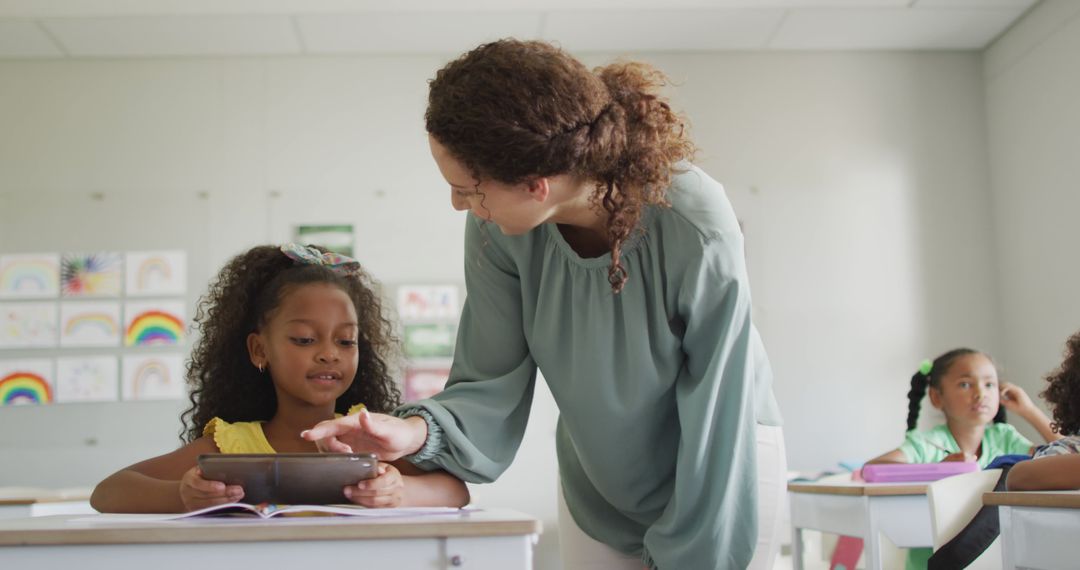 Teacher Assisting Student with Tablet in Diverse Classroom