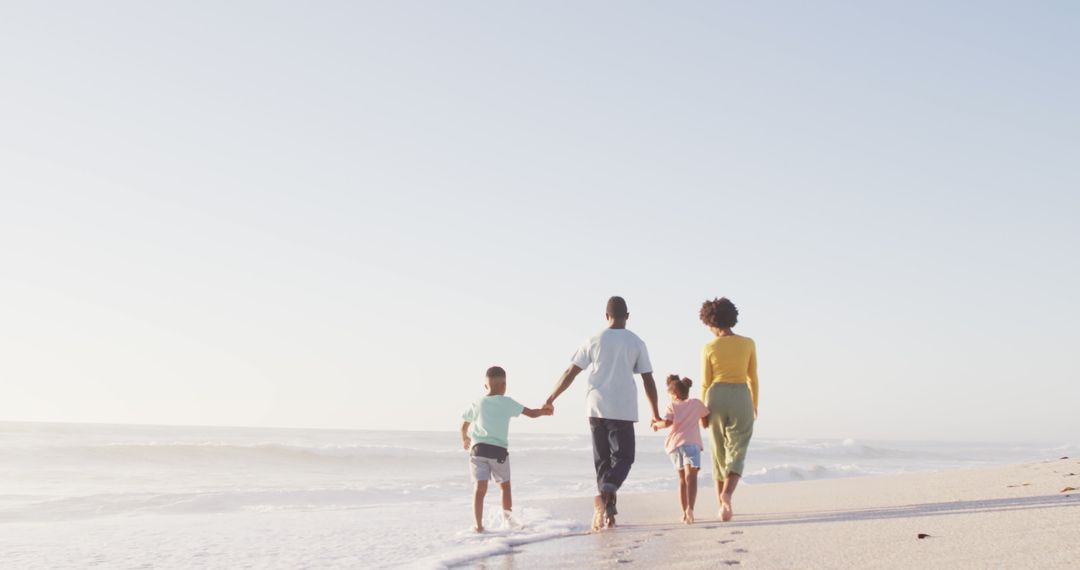 Family Strolling on Sunny Beach Holding Hands