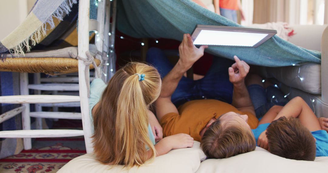 Family Enjoying Digital Device Underneath Homemade Blanket Fort - Free Images, Stock Photos and Pictures on Pikwizard.com